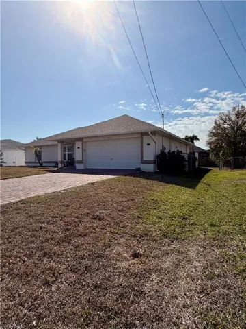 Ranch-style house with a front lawn, an attached garage, driveway, and stucco siding
