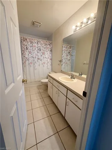 Bathroom featuring vanity, light tile patterned floors, and shower / bathtub combination with curtain