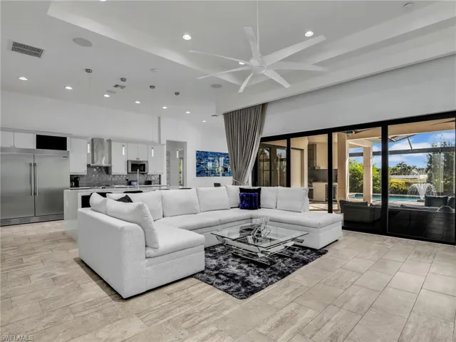 Living area with a ceiling fan, recessed lighting, a high ceiling, and light wood-style flooring