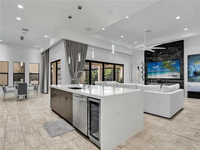 Kitchen with pendant lighting, modern cabinets, recessed lighting, wine cooler, and light stone counters
