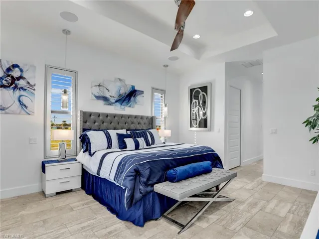 Bedroom featuring a ceiling fan, a tray ceiling, recessed lighting, and light wood-type flooring