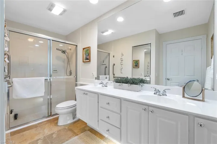 Bathroom with double vanity, a stall shower, and recessed lighting