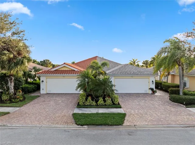 View of front of property featuring a tiled roof, driveway, and stucco siding