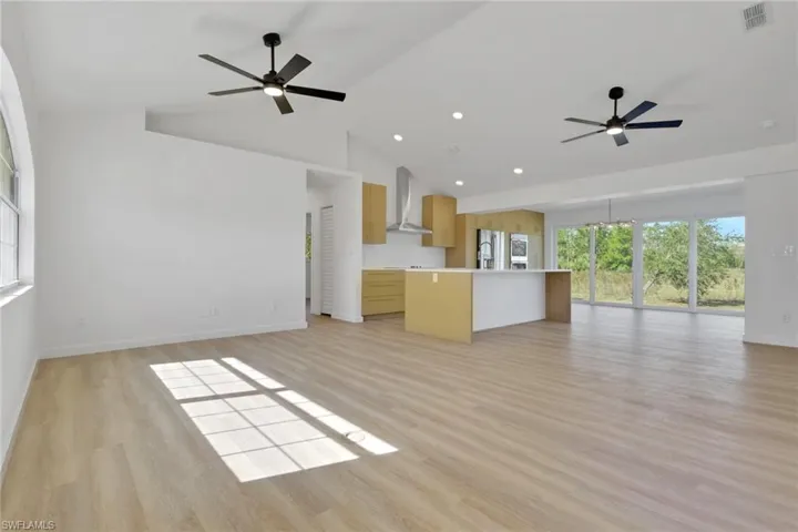 Unfurnished living room featuring a ceiling fan, light wood-style flooring, recessed lighting, and high vaulted ceiling