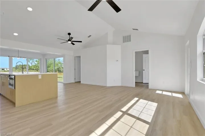 Unfurnished living room featuring light wood finished floors and high vaulted ceiling
