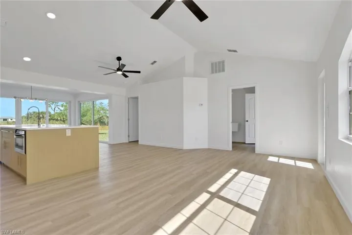 Unfurnished living room featuring light wood finished floors and high vaulted ceiling