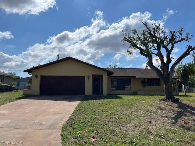 Ranch-style home with a garage and a front lawn