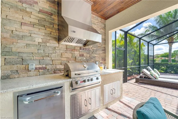 View of patio with area for grilling, exterior kitchen, and a lanai