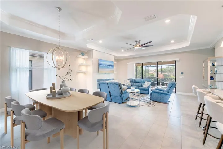 Dining area with a tray ceiling, a chandelier, crown molding, a ceiling fan, and recessed lighting
