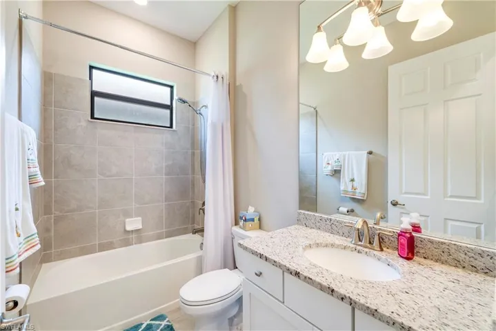 Full bath featuring shower / bath combination with curtain, toilet, vanity, and a chandelier