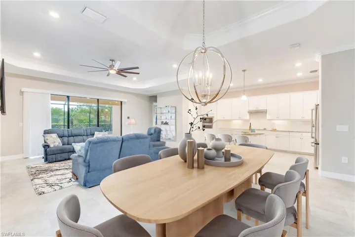 Dining area featuring a raised ceiling, ornamental molding, light tile patterned floors, a chandelier, and baseboards