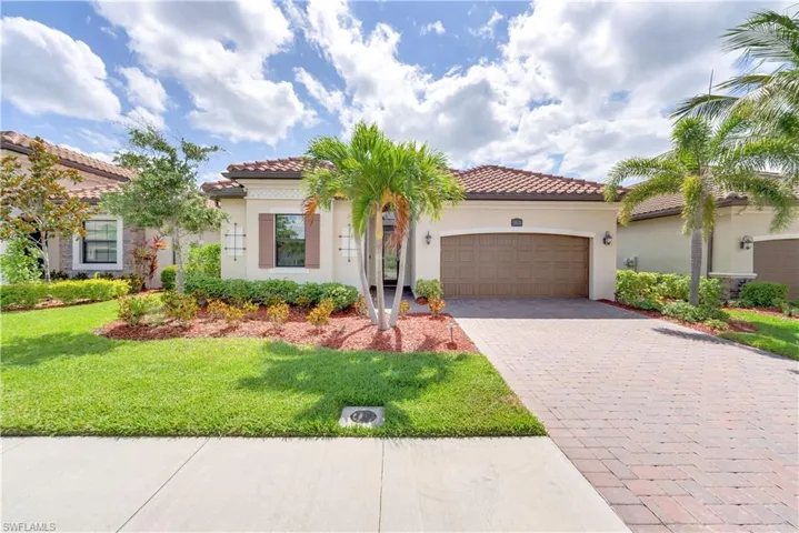 Mediterranean / spanish-style home with decorative driveway, an attached garage, a front yard, and stucco siding