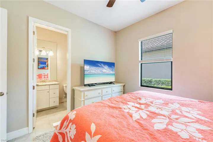 Bedroom with connected bathroom, baseboards, and a ceiling fan