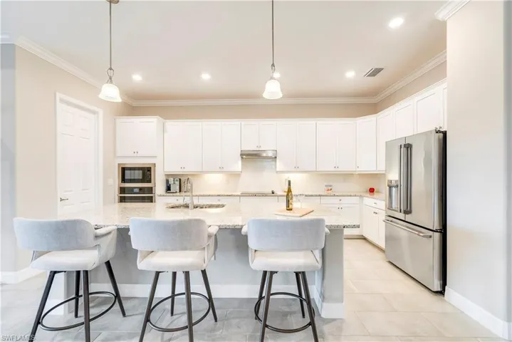 Kitchen featuring black appliances, a sink, ornamental molding, baseboards, and under cabinet range hood