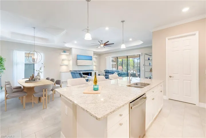 Kitchen featuring a sink, stainless steel dishwasher, a raised ceiling, light tile patterned flooring, and ornamental molding