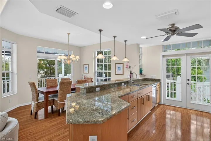 Kitchen with a peninsula, dark stone counters, french doors, light wood-style floors, and a chandelier