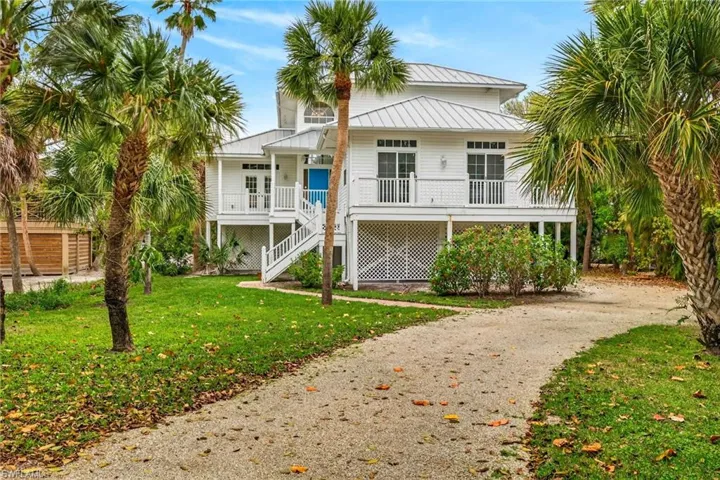 Front of property featuring a metal roof, a yard, driveway, and a wooden deck