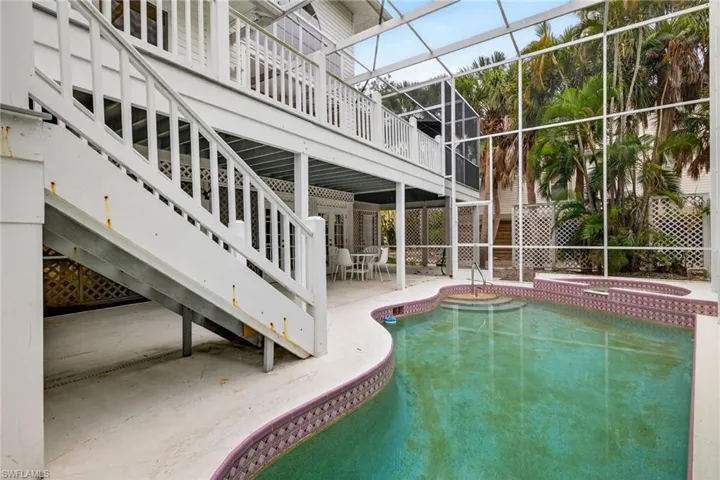 Outdoor pool featuring a patio, glass enclosure, an in-ground hot tub, and a sunroom