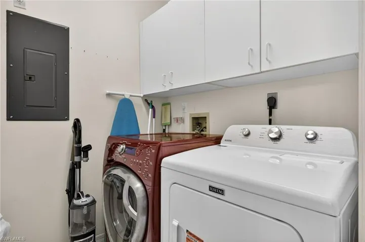 Laundry area featuring electric panel, cabinet space, and independent washer and dryer