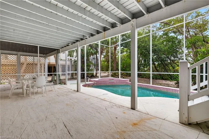 Relaxing pool / spa featuring a patio area, outdoor dining area, and glass enclosure