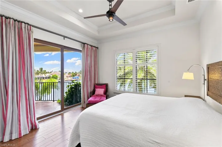 Bedroom with hardwood / wood-style flooring, ceiling fan, a tray ceiling, ornamental molding, and access to outside