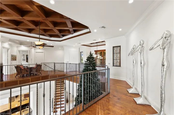 Corridor with beam ceiling, coffered ceiling, crown molding, and hardwood / wood-style floors