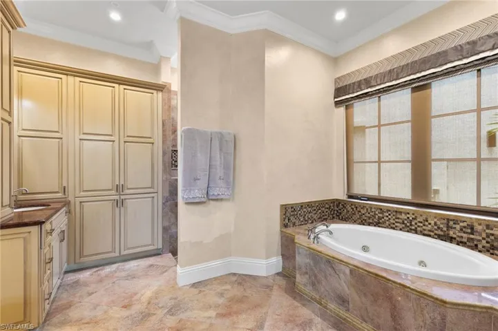 Bathroom featuring a relaxing jetted tub, walk in shower and dual vanities.