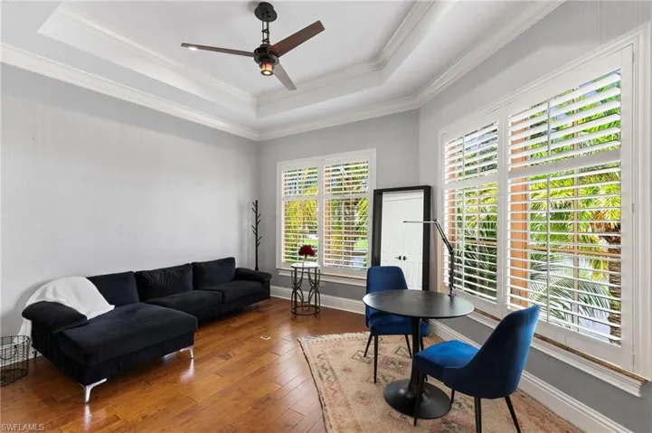 Guest bedroom featuring plenty of natural light, hardwood / wood-style flooring, and a raised ceiling