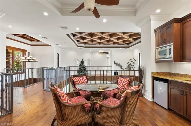 Loft featuring hardwood / wood-style flooring, wet bar, coffered ceiling, and ornamental molding