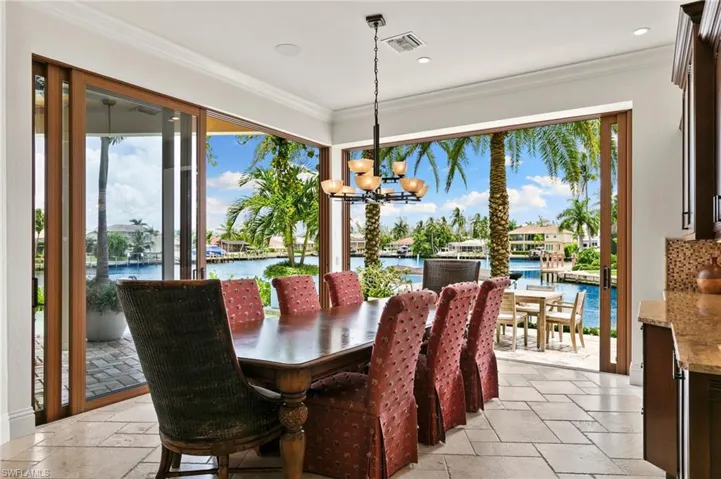 Dining space with a notable chandelier, a water view, and crown molding