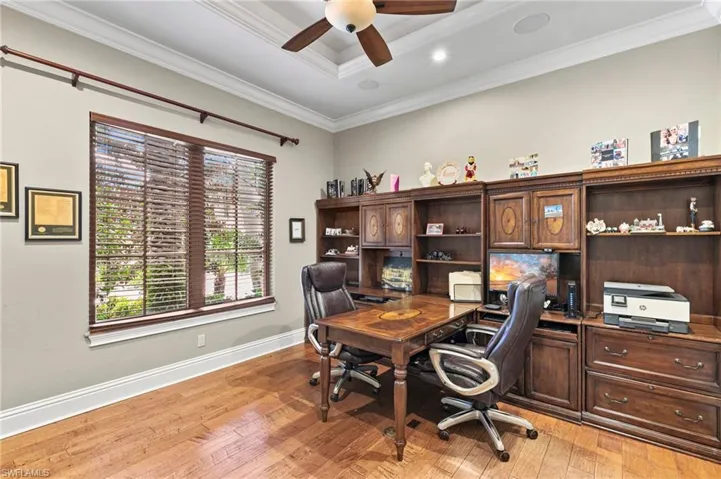 Home office with a tray ceiling, light hardwood / wood-style flooring, ceiling fan, and ornamental molding
