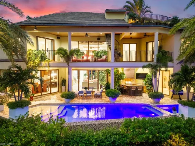 Back house at dusk featuring a balcony, a patio, and ceiling fan