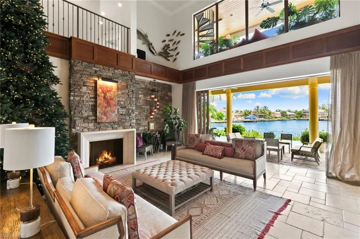 Living room with a water view, stone floors, a towering ceiling, and ceiling fan