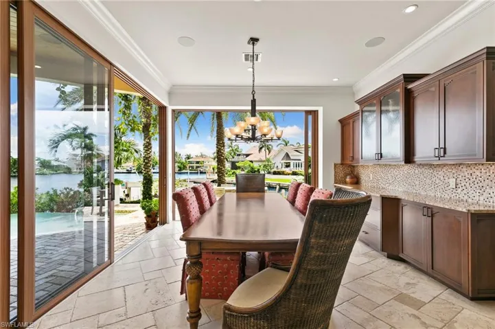 Dining space with a water view, crown molding, a notable chandelier, and travertine stone floors