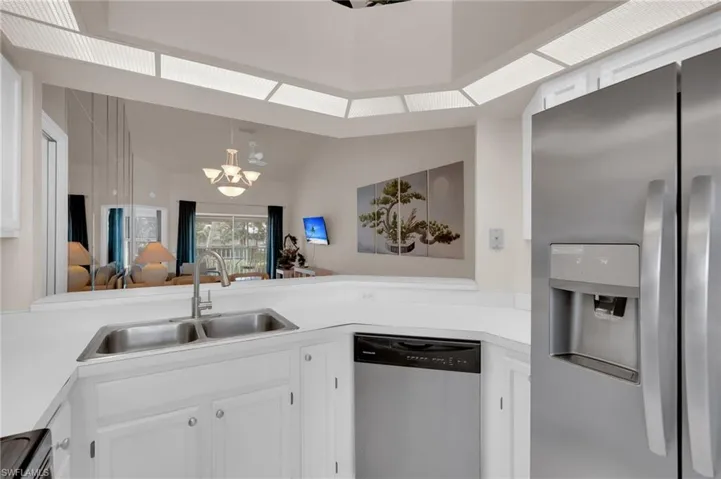 Kitchen featuring appliances with stainless steel finishes, white cabinetry, light countertops, and a chandelier