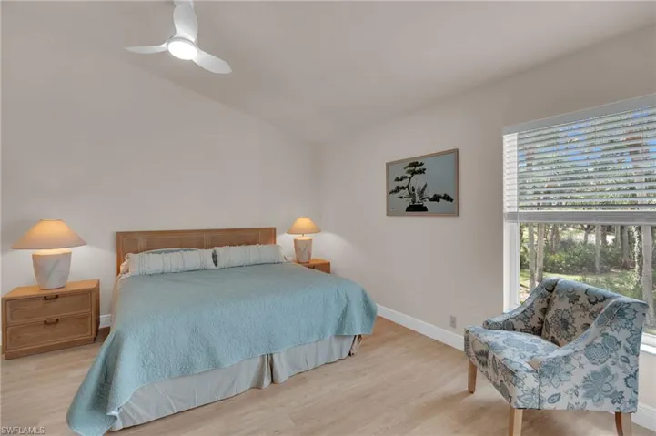 Primary bedroom with wood finished floors, a ceiling fan, and lofted ceiling