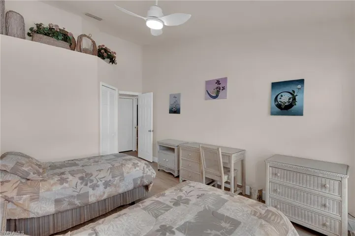 Bedroom with wood finished floors, a ceiling fan, a high ceiling, and a closet