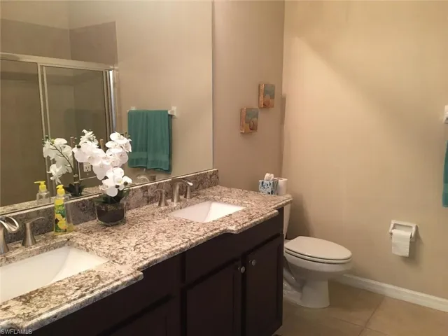 Bathroom featuring tile patterned floors, toilet, a stall shower, and a sink