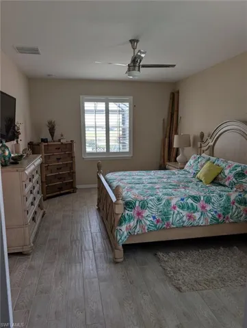 Bedroom featuring a ceiling fan, visible vents, baseboards, and light wood-style floors