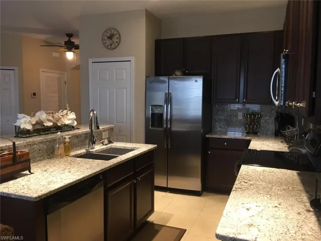 Kitchen featuring tasteful backsplash, appliances with stainless steel finishes, ceiling fan, a sink, and a center island with sink
