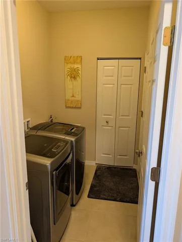 Clothes washing area featuring light tile patterned floors, laundry area, and washing machine and dryer