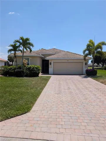 Ranch-style house featuring an attached garage, a front yard, decorative driveway, and stucco siding