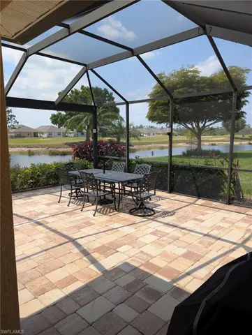 View of patio with a lanai, outdoor dining area, and a water view