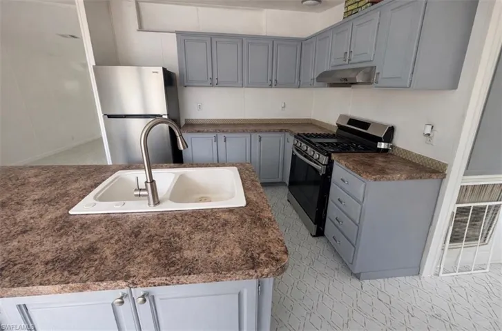 Kitchen featuring gray cabinets, stainless steel appliances, and dark countertops