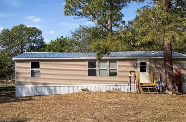 Back of property with a lawn and a metal roof