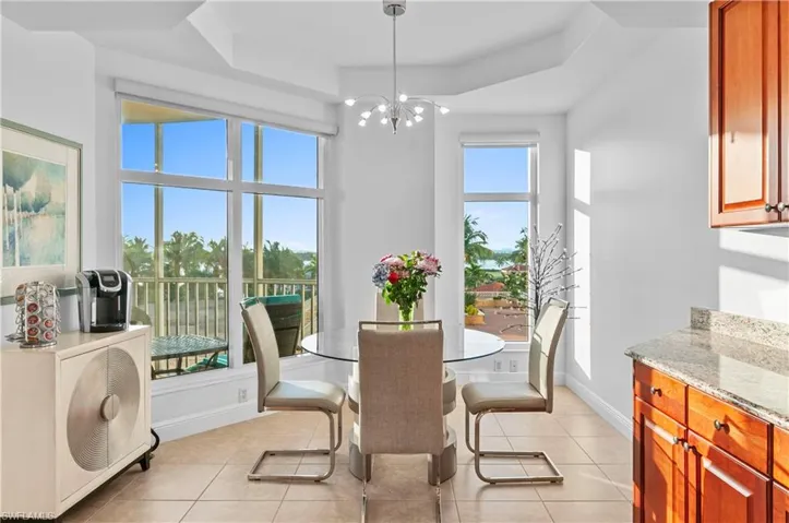Dining space with light tile patterned floors, a chandelier, and a raised ceiling