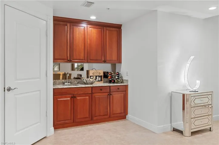 Bar with light stone counters, recessed lighting, brown cabinets, and light tile patterned flooring