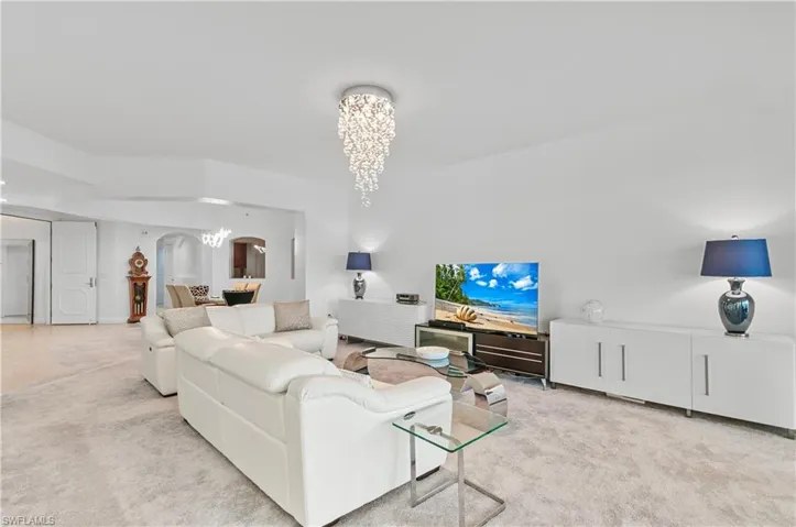 Carpeted living area with a chandelier and arched walkways