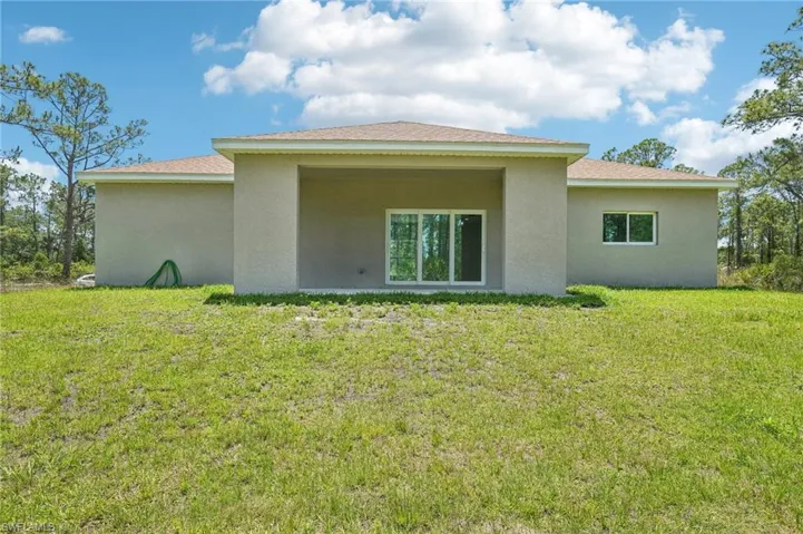 Back of house with stucco siding and a yard