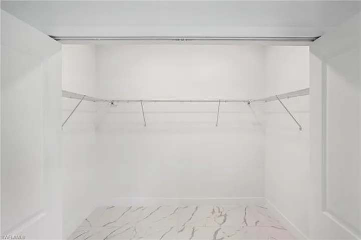 Walk in closet with light marble finish floors